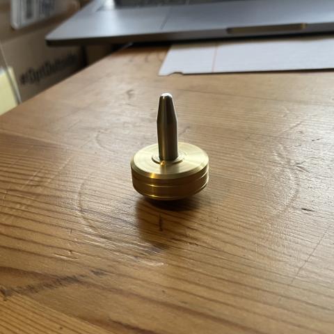 brass top spinning on a tabletop, looking like it's balanced and motionless