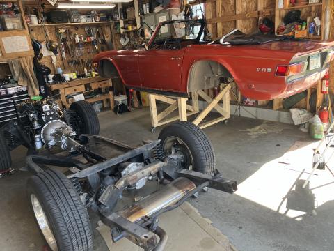 TR6 chassis is on the garage floor, the body is separate on a wooden stand