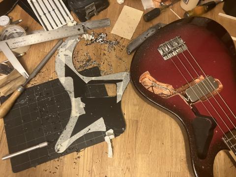 workbench with an pickguard being shaped, and piles of plastic shavings