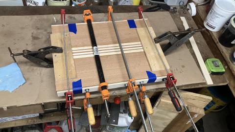 wood panels being glued, with many clamps and support boards