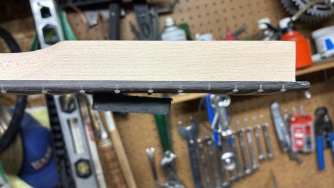 heel end of a guitar neck, facing down, with a magnet partially attached