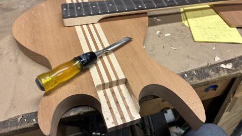 body with rectangular shape cut out for the neck attachment, with wood chisel nearby
