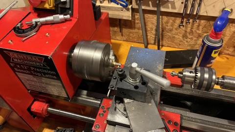 small red metal lathe spinning into a blur, with a piece of aluminum stock in the chuck