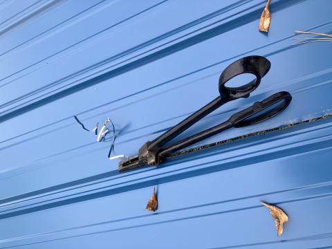 pair of tin snips cutting a blue painted metal panel