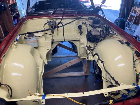 the empty engine bay of a TR6, freshly painted in a pale yellow